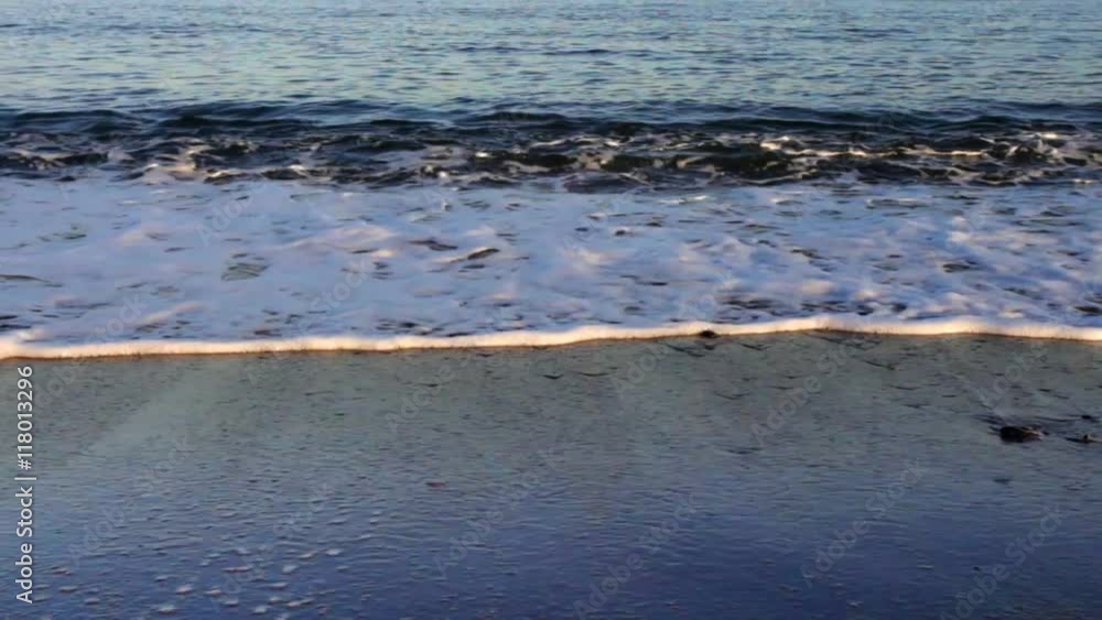 waves lapping onto beach with sunlight reflections waves lapping onto beach with sunlight reflections