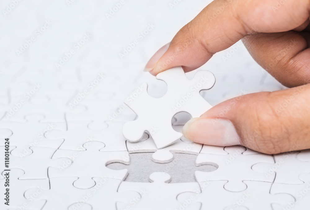 Fototapeta premium Close up of hand placing the last jigsaw puzzle piece, Hand hold