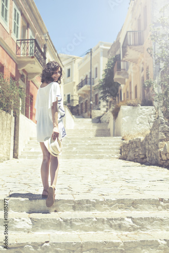 Beautiful girl bathed in sunshine walking in ancient city Symi © BrunoWeltmann