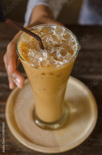 Glass of iced coffee against women's hand. Selective Focus.