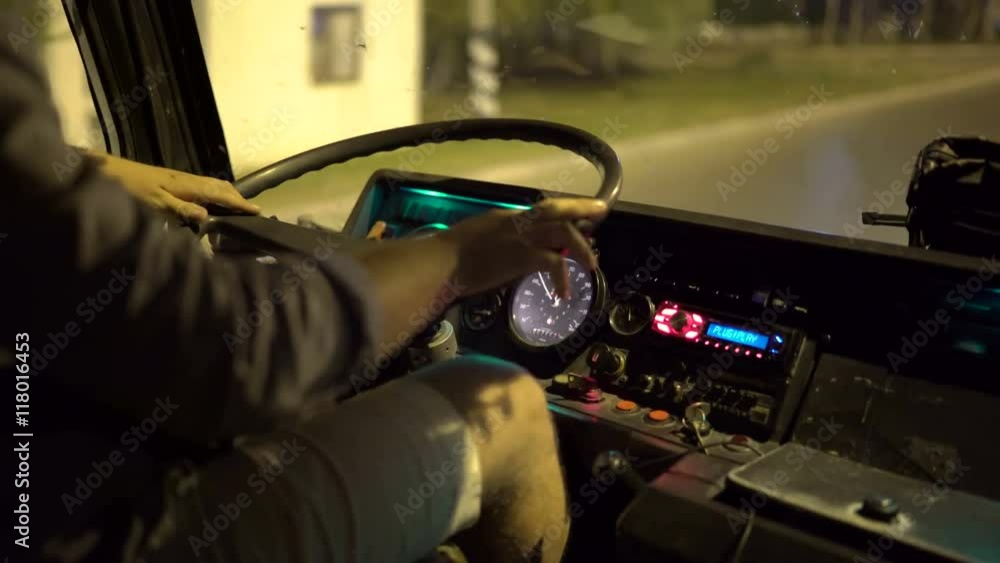 Bus driver behind the wheel of intercity coach riding on a city street at night Bus driver behind the wheel of intercity coach riding on a city street at night