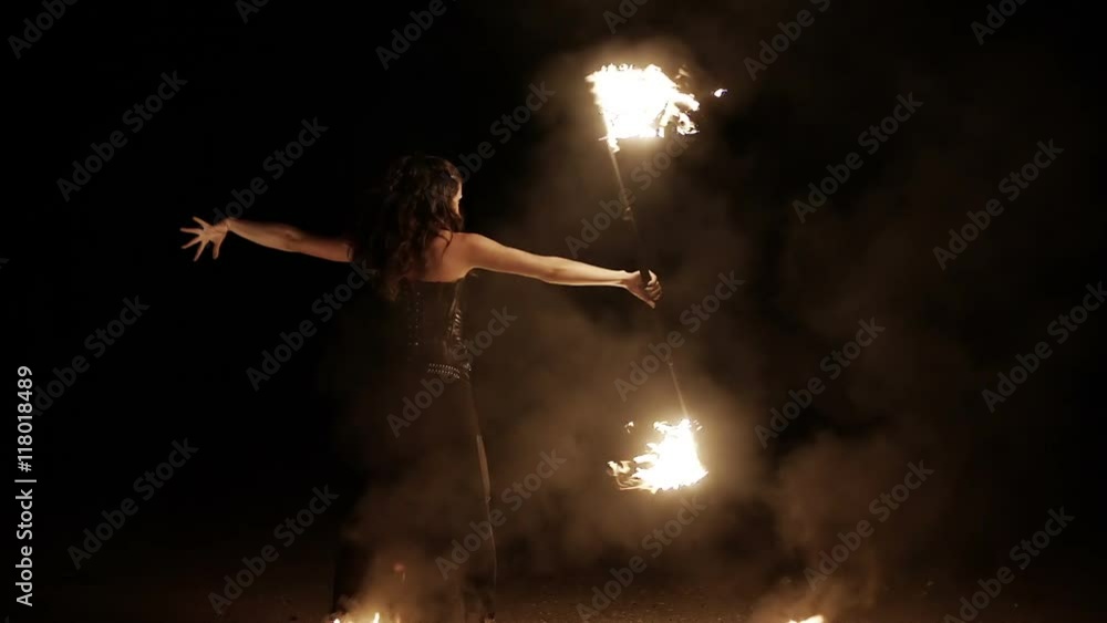 Female fire dance performer dancing with burning fire on black background. Brunette woman juggles with fireballs dance show outdoors Female fire dance performer dancing with burning fire on black background. Brunette woman juggles with fireballs dance show outdoors