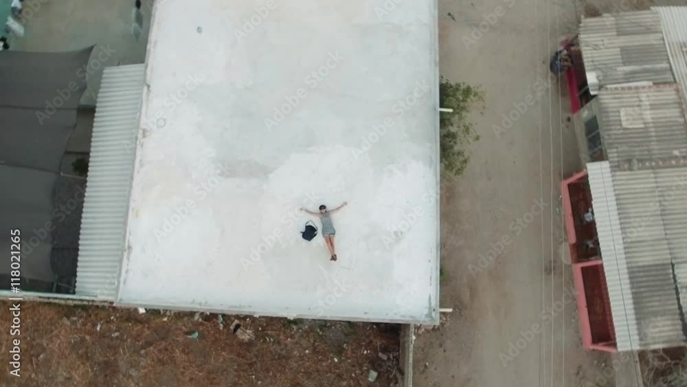 Aerial shot of woman lay down on roof in a poor neighborhood. 4k Aerial shot of woman lay down on roof in a poor neighborhood. 4k