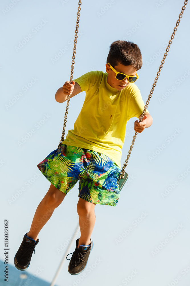 Boy playing swinging by swing-set.