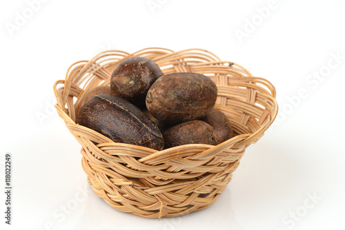 Nutmeg, spices, medicinal properties in a basket on a white background.