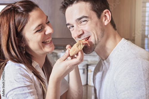 Happy young couple eating pizza at the kitchen