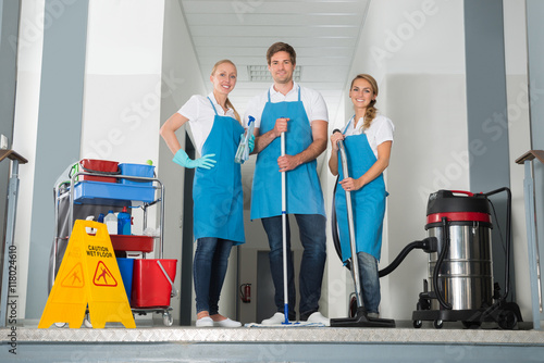 Portrait Of Janitors Holding Cleaning Equipments