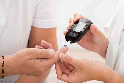 Doctor Using Glucometer On Patient's Finger photo