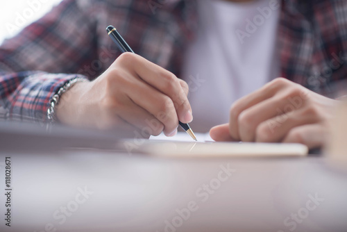 A business man is taking notes into a notebook with an alarm clo