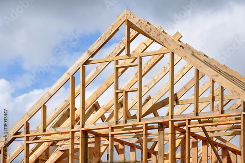 The process of construction of a frame private house with a pitched roof. Wooden frame on the blue sky background.