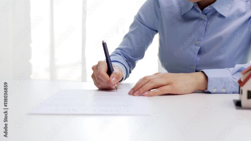 woman with house model and pen signing contract woman with house model and pen signing contract
