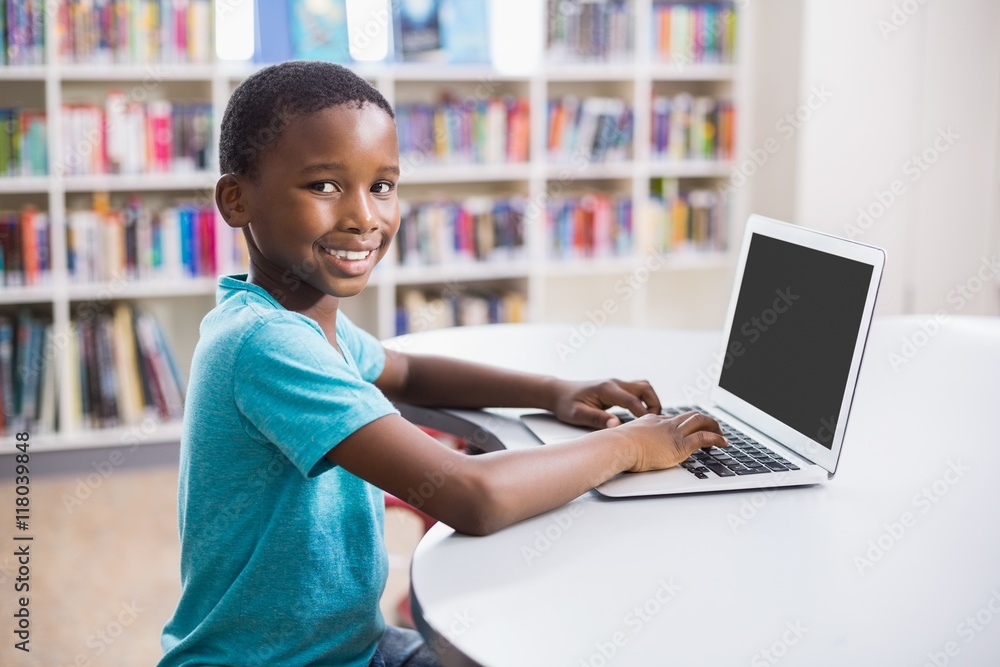 Schoolboy using laptop in library Schoolboy using laptop in library