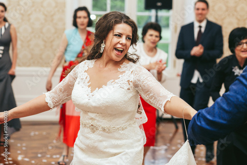 Bride laughs while dancing with a groom in restaurant