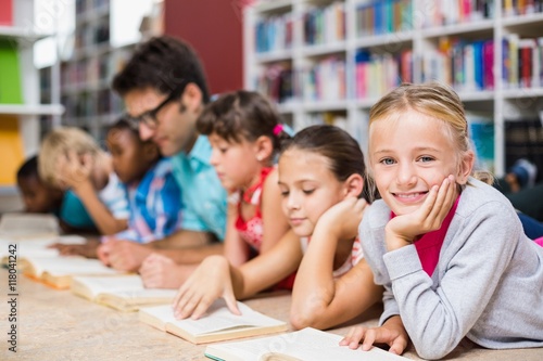 Teacher and kids reading book in library