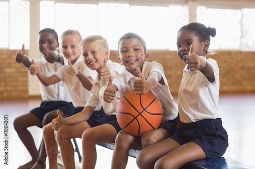 Smiling students with basketball showing thumbs up