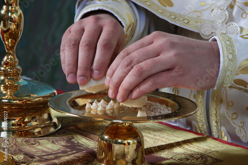 Hands of priest consecrates bread during orthodox liturgy ceremony