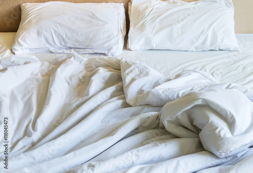Messy white bed sheets and white pillows in the morning.