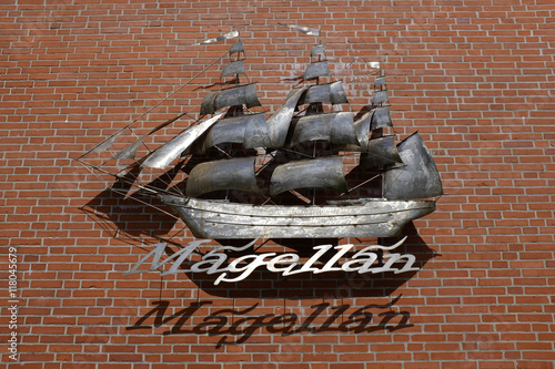 metal sculpture of an old three-master sailer on brick wall labeled with the discoverers name  Magellan