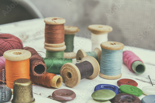 Set of several pied buttons for garment with threads on a bright wooden background. Toned and processing photos with soft focus in vintage style. photo