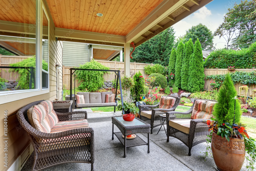 Fototapeta premium Cozy covered sitting area with wicker chairs and swing
