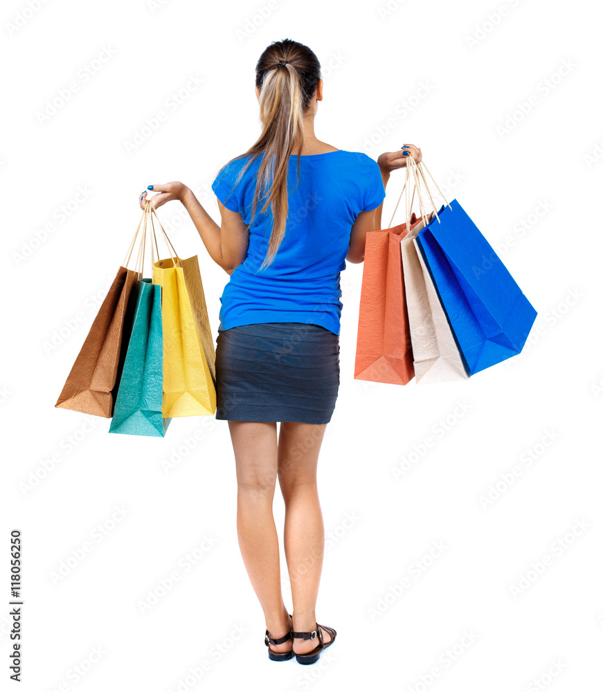 back view of woman with shopping bags. backside view of person.  Rear view people collection. Isolated over white background. girl in a short skirt and a blue shirt holding colored bags with purchases