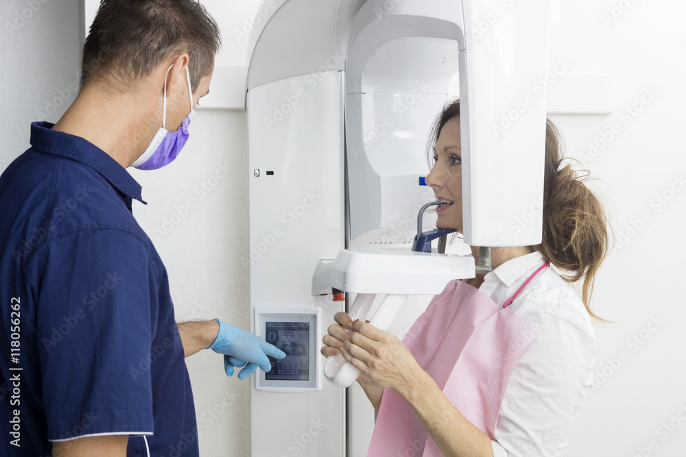 Male Dentist Taking Xray Of Patient's Teeth Using Panoramic Mach Male Dentist Taking Xray Of Patient's Teeth Using Panoramic Mach