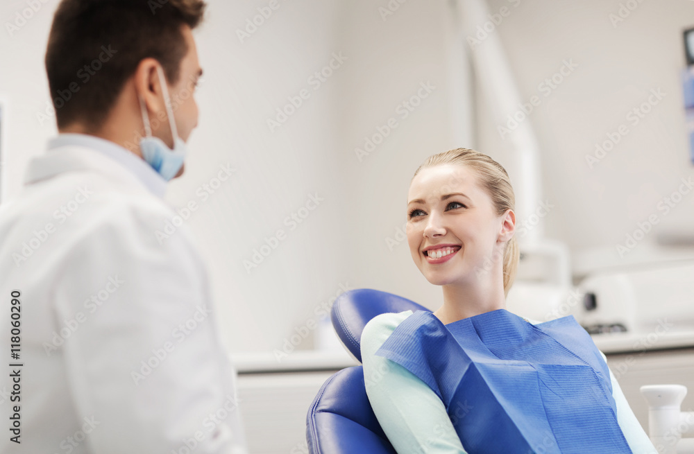 Fototapeta premium happy male dentist with woman patient at clinic