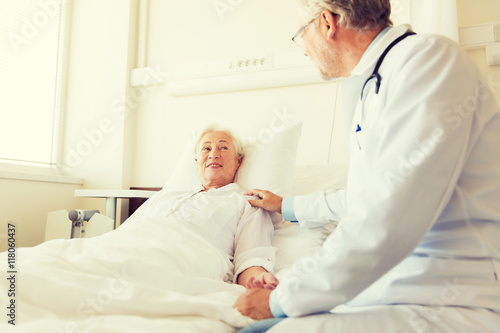 doctor visiting senior woman at hospital ward