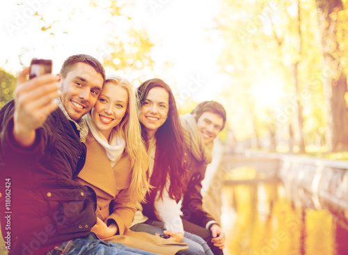 group of friends with photo camera in autumn park