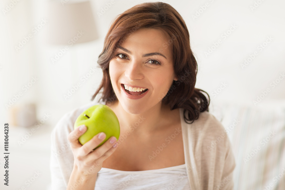 smiling young woman eating green apple at home smiling young woman eating green apple at home