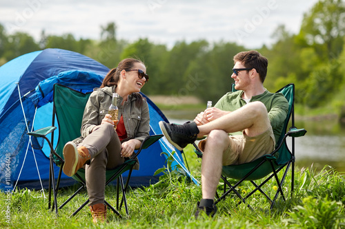 happy couple drinking beer at campsite tent