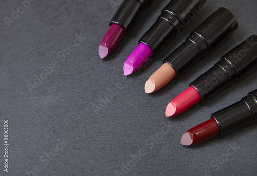 Lipsticks arranged on a dark slate background forming a page border