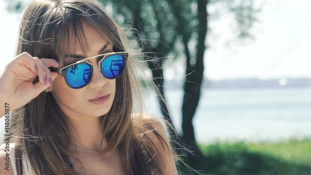 Beautiful and sexy girl in a swimsuit undresses sunglasses and smiling. Slowly Beautiful and sexy girl in a swimsuit undresses sunglasses and smiling. Slowly