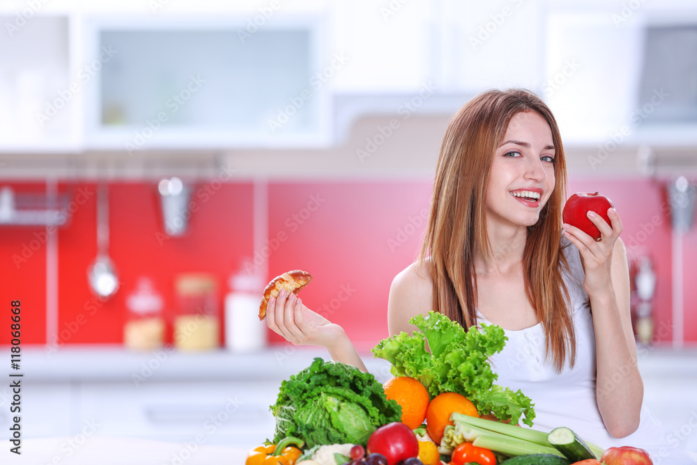 Woman choosing between croissant and an apple Woman choosing between croissant and an apple