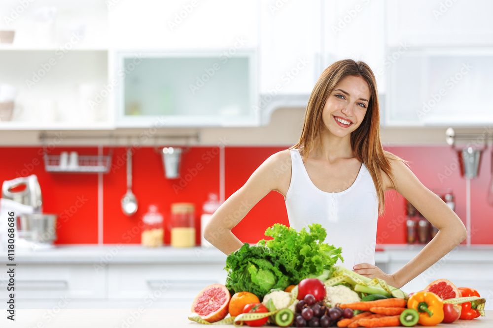 Young woman with fresh vegetables and fruits in kitchen. Diet concept
