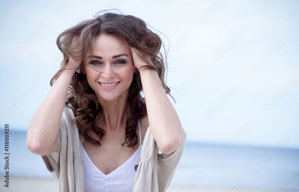 Happy woman on the beach Portrait of the beautiful girl close-up, the wind fluttering hair