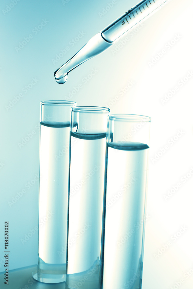 Close up of a pipette dropping a blue sample into a test tube Close up of a pipette dropping a blue sample into a test tube