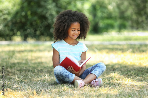 Cute girl reading book on g...