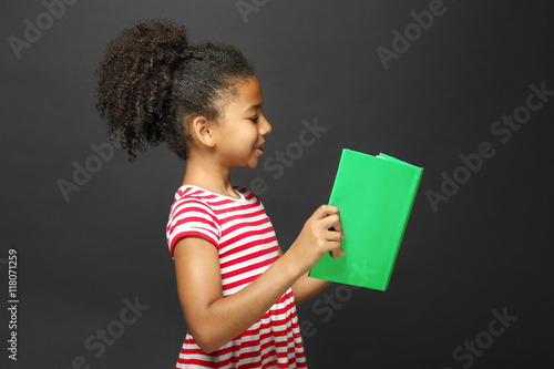Cute girl reading book on g...