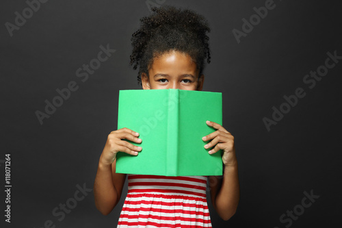 Cute girl reading book on g...