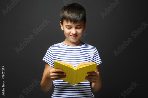 Cute boy reading book on gr...
