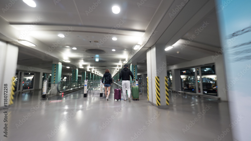 People with luggage walking on the moving walkway at the airport terminal of Seoul, South Korea