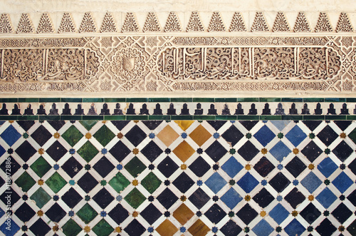 Moorish pattern from Alhambra, Granada, Spain - Closeup of a plaster wall with islamic motif and geometric tiles