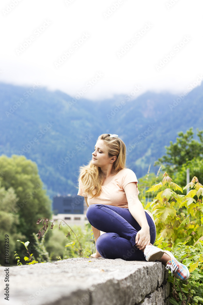 Beautiful young girl on the nature in the highlands. Young girl outdoors alone. Dreamy girl sitting near the country house

