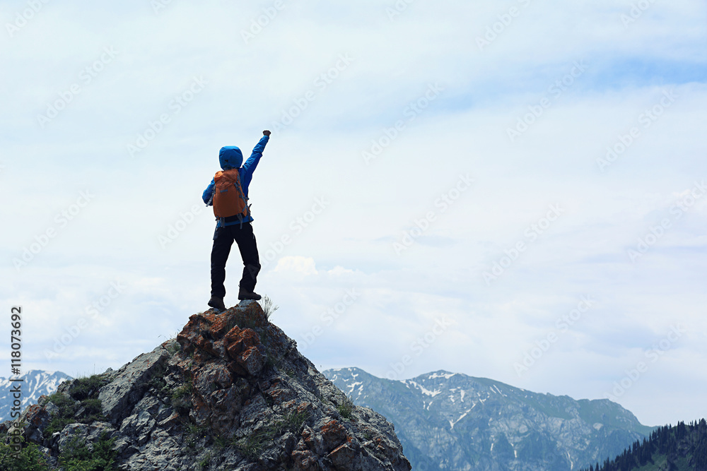 successful young woman backpacker open arms on mountain peak