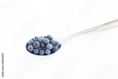 Ripe blueberries in a metal spoon on white background