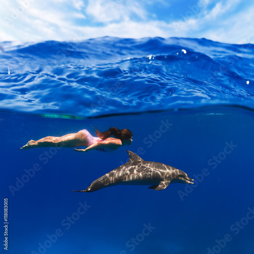 swimmer girl in pink swimsuit and dolphin playing in the sea underwater