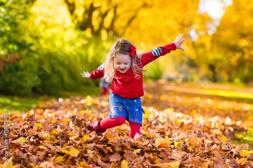 Little girl playing in autumn park