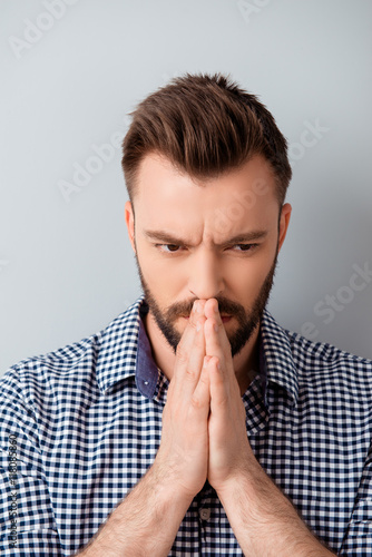 Portrait of young concentrated bearded man praying and waiting