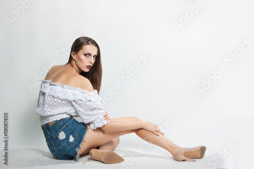 young beautiful girl in shorts and blouse posing in studio